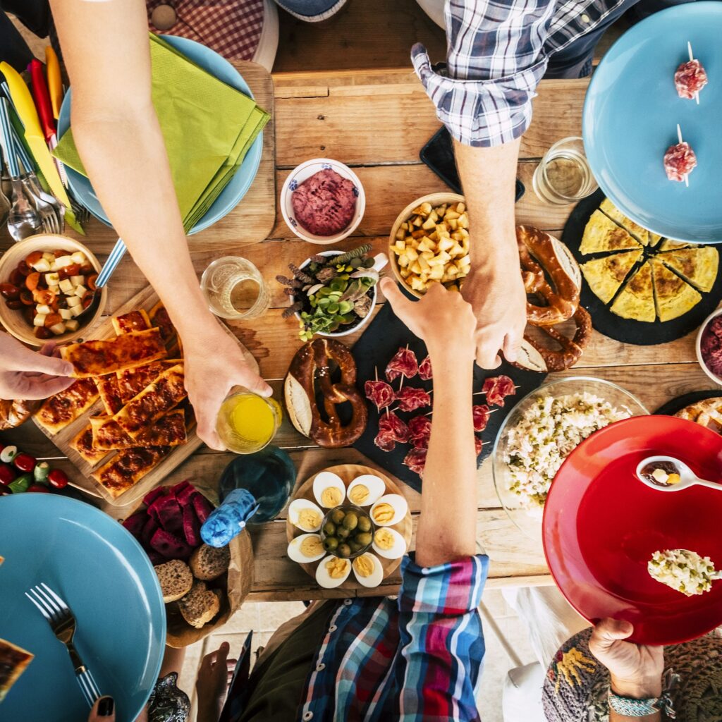 Vertical view of group of friends family eating together on a wooden table full of food